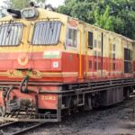 Vibrant locomotive in India captured on railway tracks surrounded by greenery.
