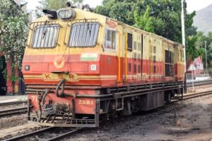 Vibrant locomotive in India captured on railway tracks surrounded by greenery.