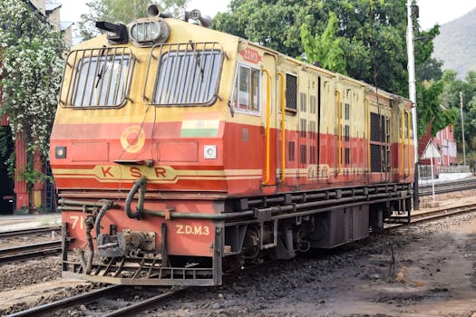 Vibrant locomotive in India captured on railway tracks surrounded by greenery.