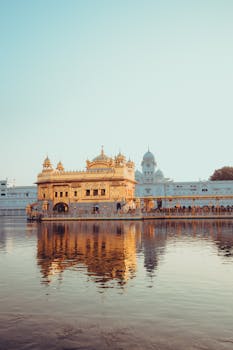 A serene view of the Golden Temple in Amritsar, its reflection shimmering in the tranquil water at sunrise.