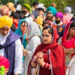 A colorful gathering of Sikh men and women outdoors in traditional attire.