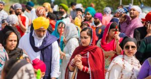 A colorful gathering of Sikh men and women outdoors in traditional attire.