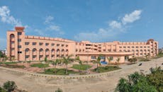 Large educational building with clear blue sky and landscaped grounds.