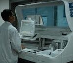 A lab technician operates a clinical analyzer in a modern laboratory setting.