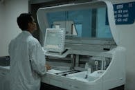 A lab technician operates a clinical analyzer in a modern laboratory setting.